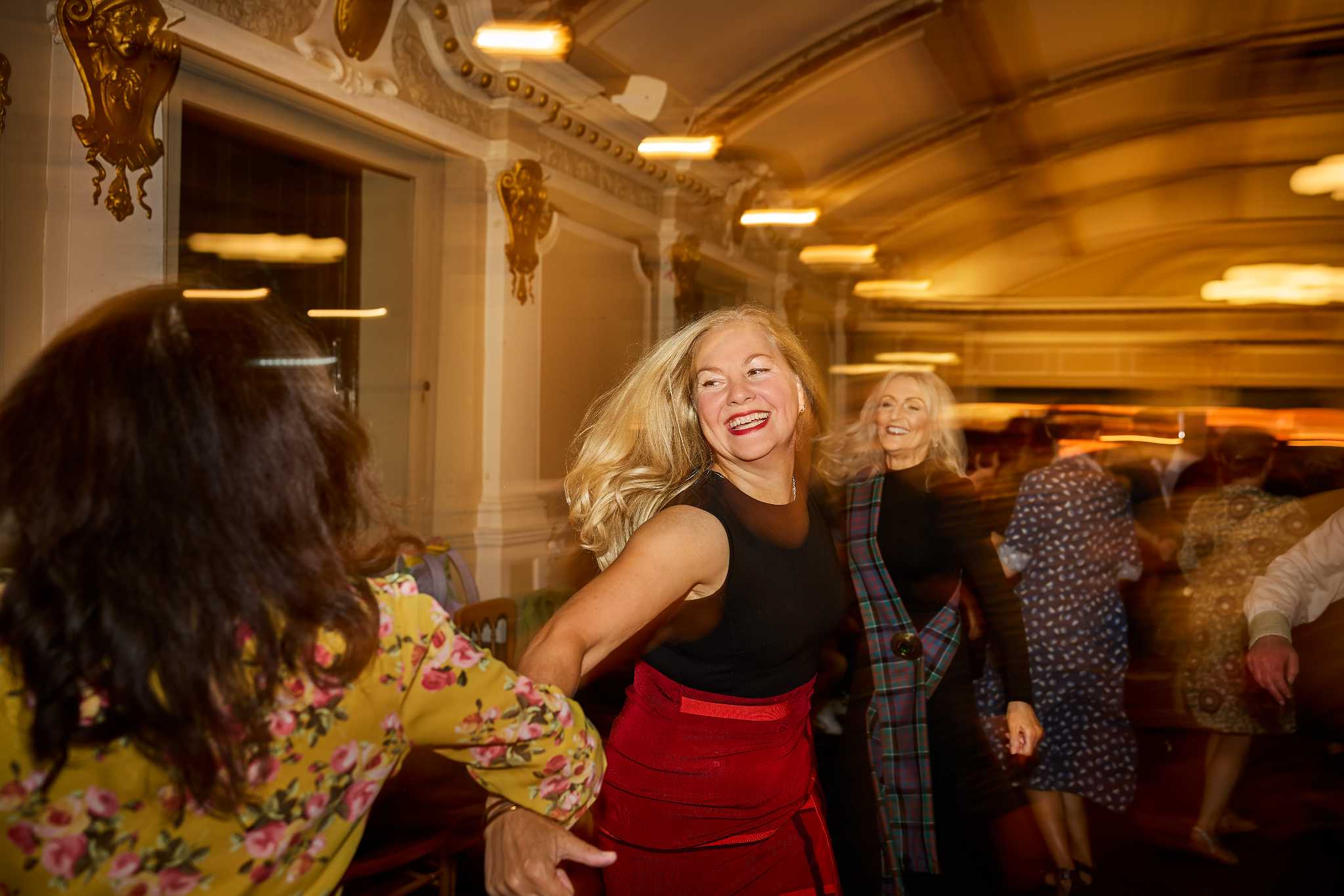 Dancers enjoying ceilidh dancing with focus on a woman grinning broadly.