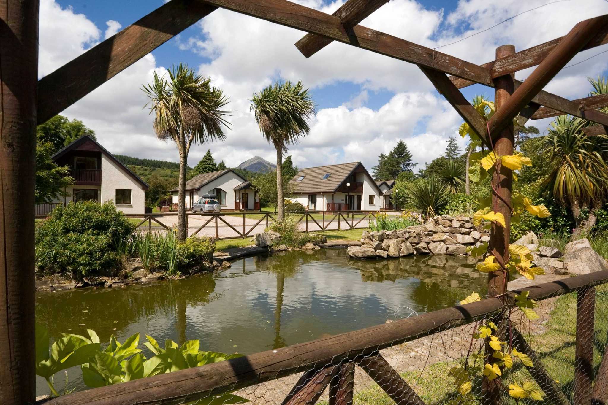 Looking across a picturesque pond through tress to lodges on the other side