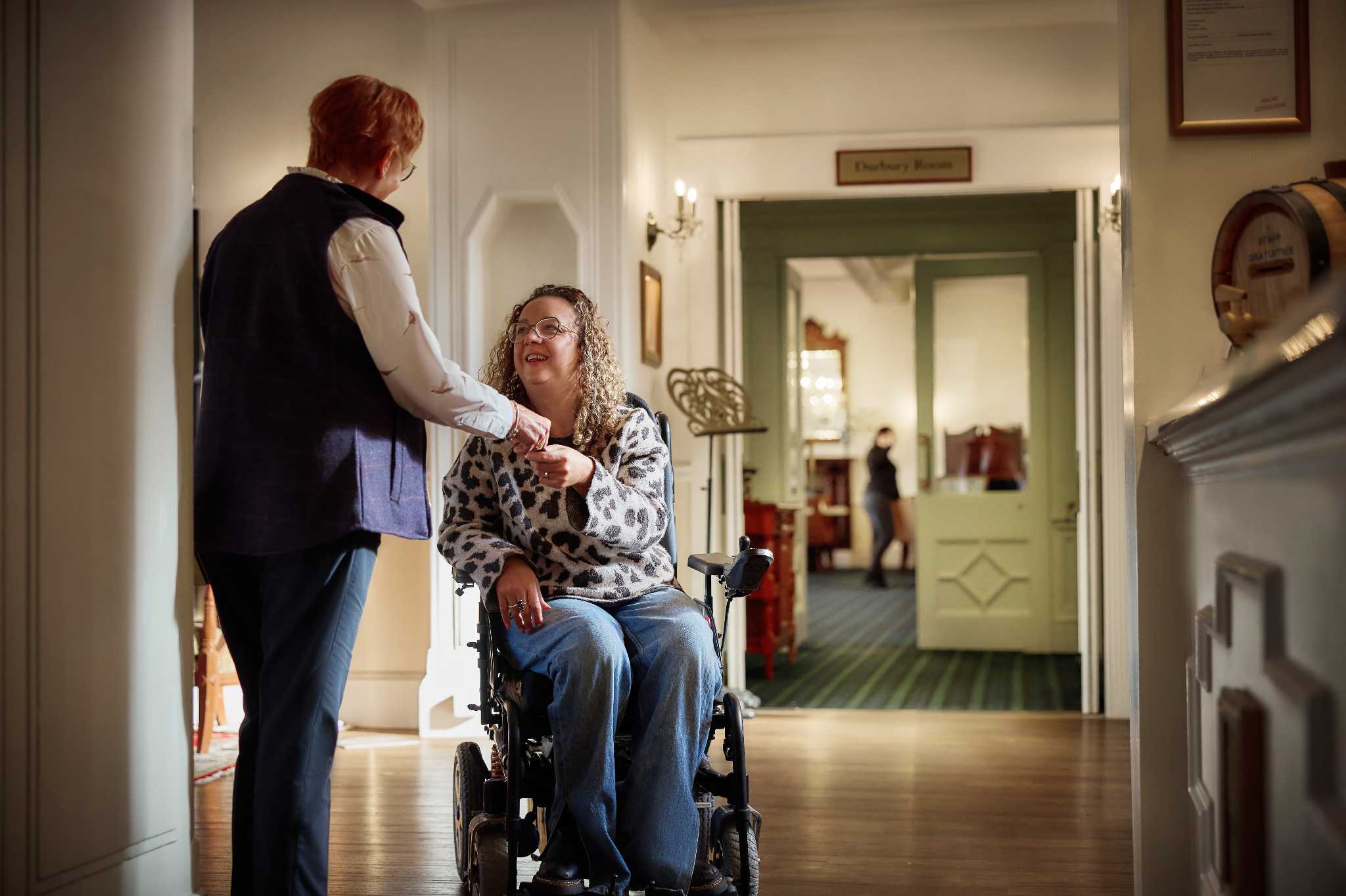 A lady in a wheelchair is engaging with a member of staff