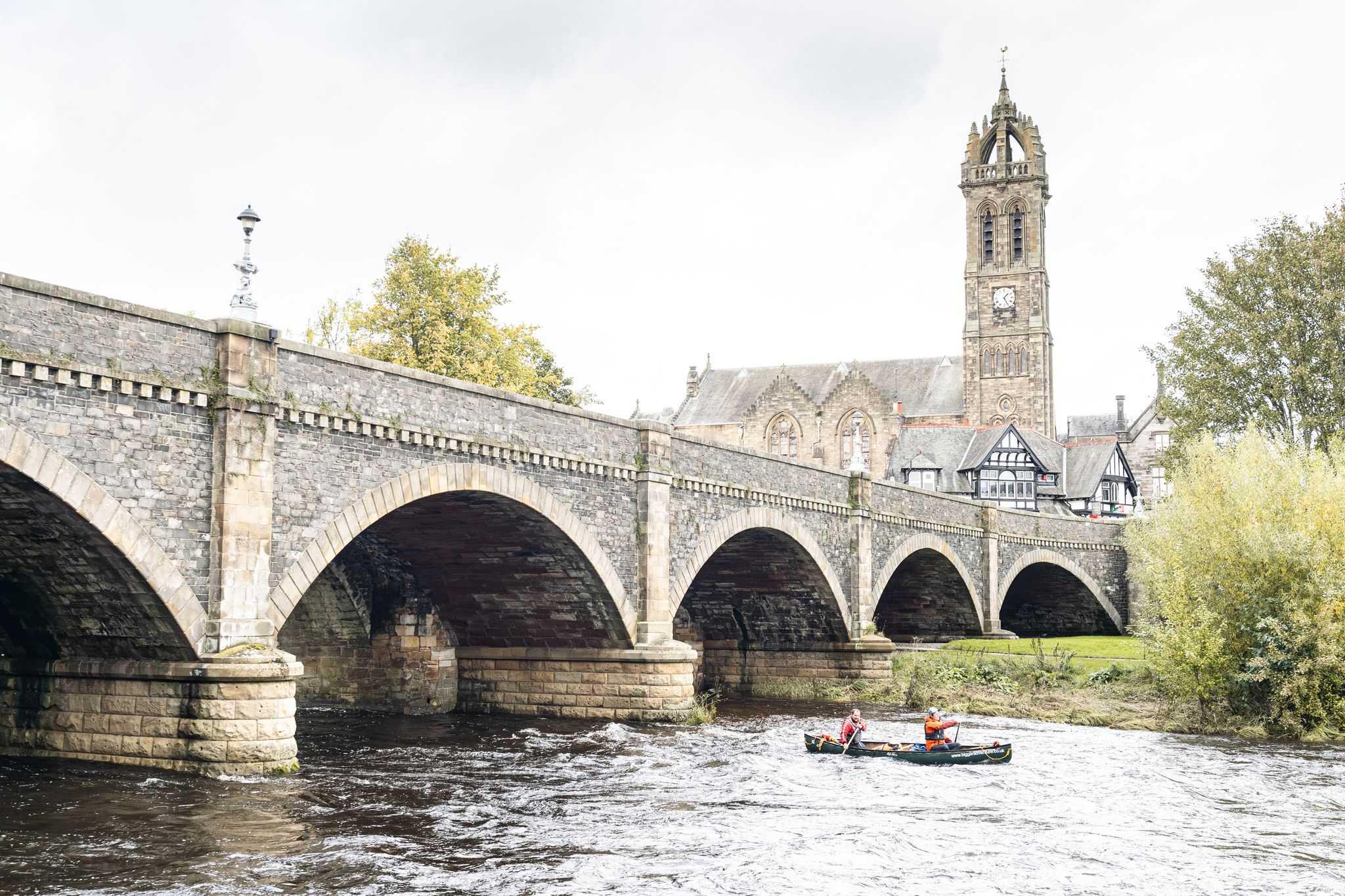 Canoeists pass under a bridge