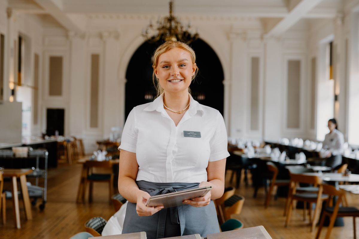 A uniformed waitress presents a menu