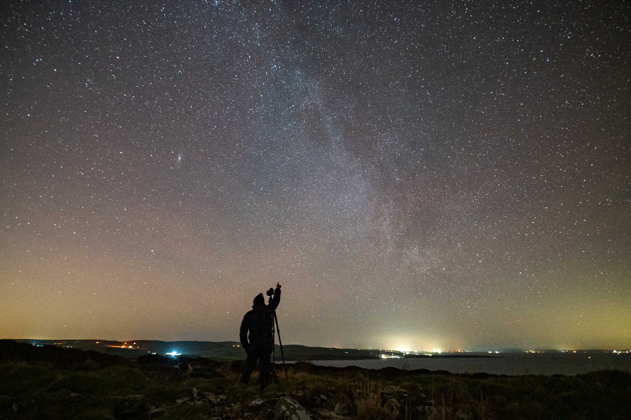 A silhouetted man points to a starry night sky