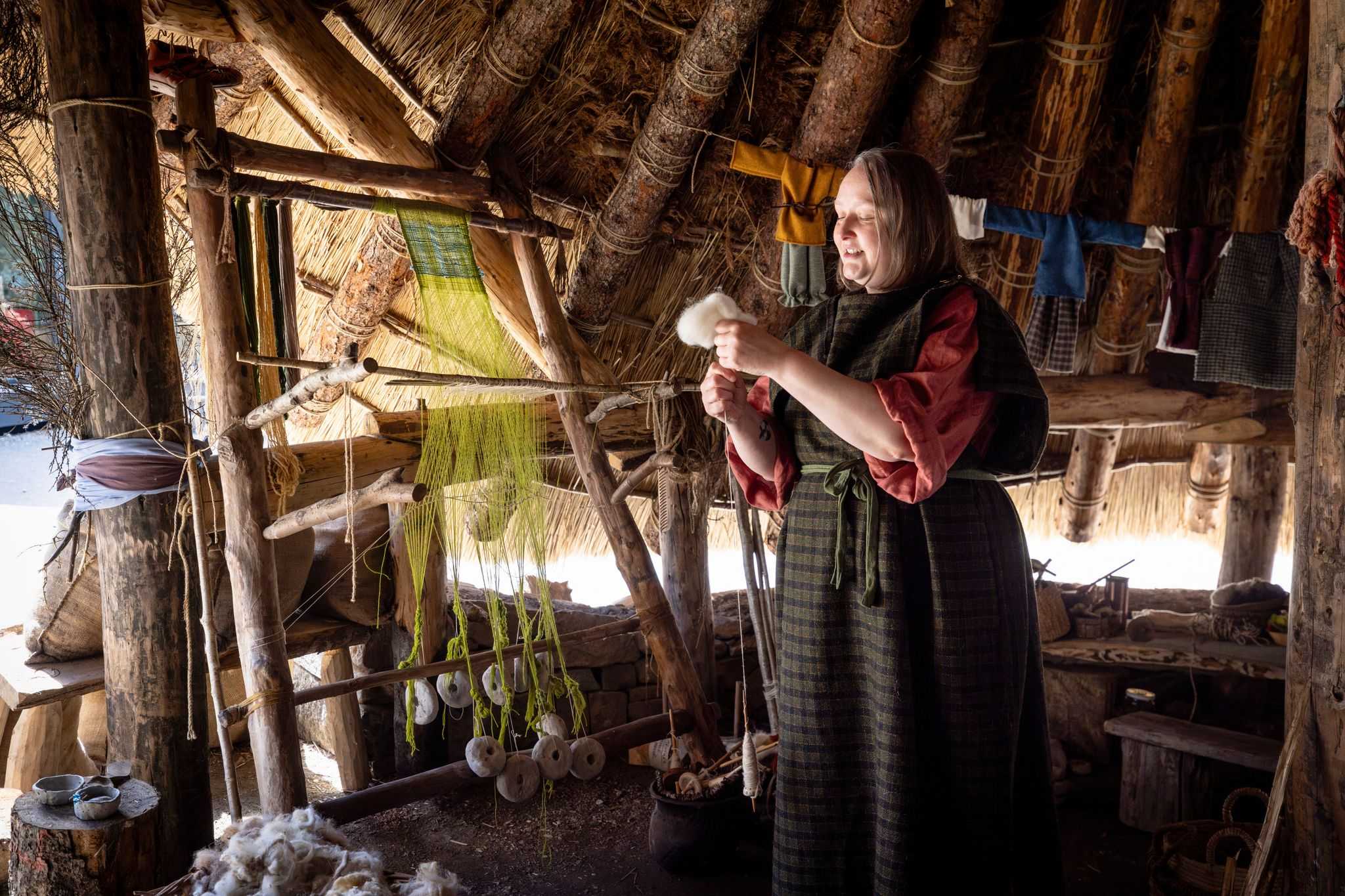 A lady in iron age costume works at yarn