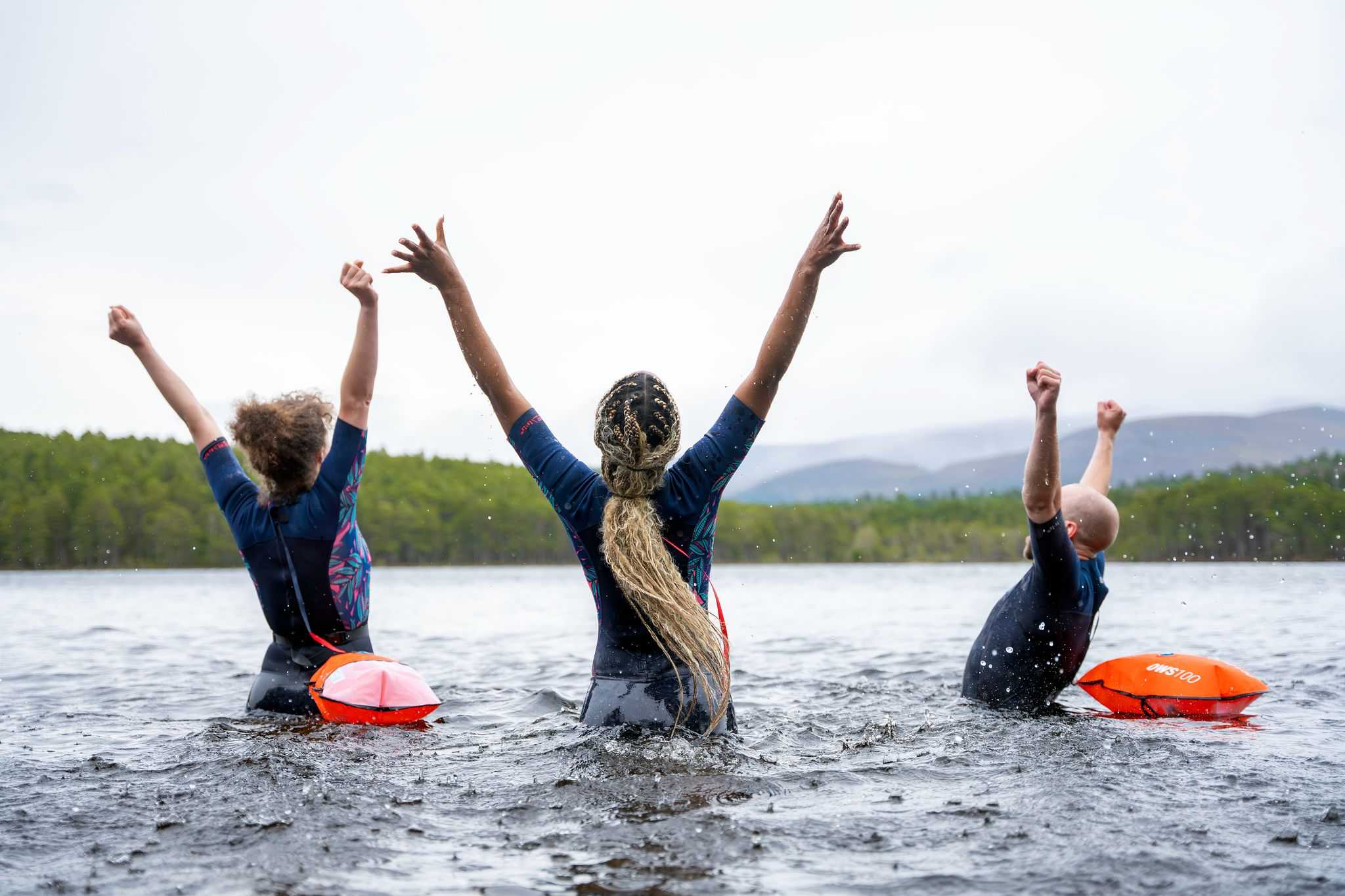 Three people in a loch.They are enjoying themselves and are attached to flotation devices.