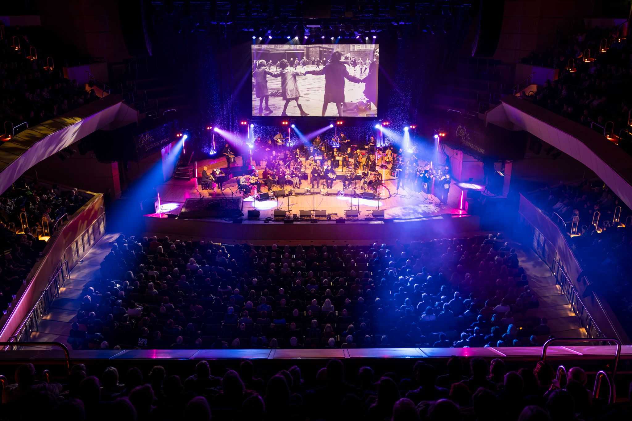 Looking down from a balcony towards a stage where performers are lit up.