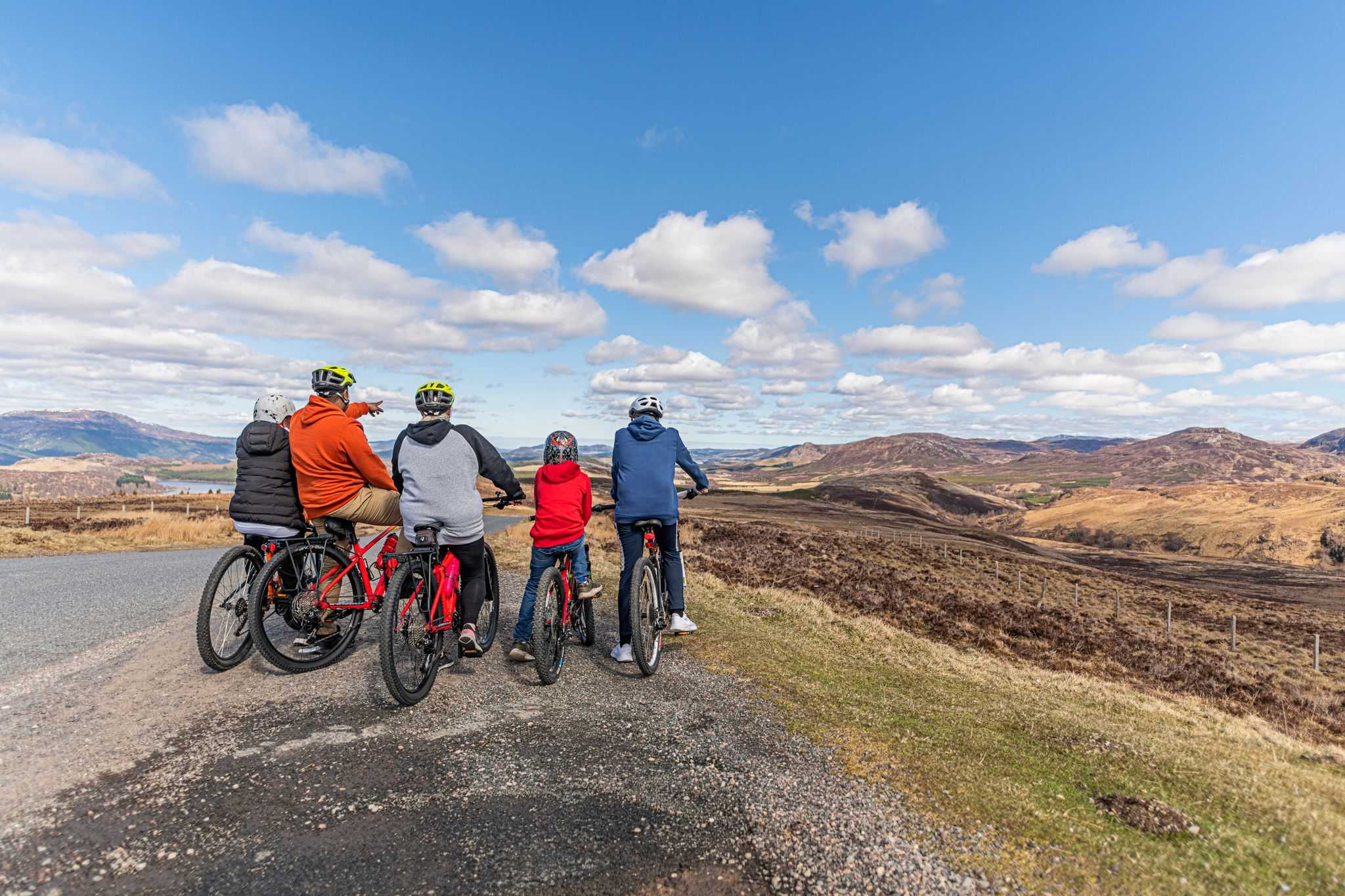 A family of cyclists look out from a viewpoint at the the countryside
