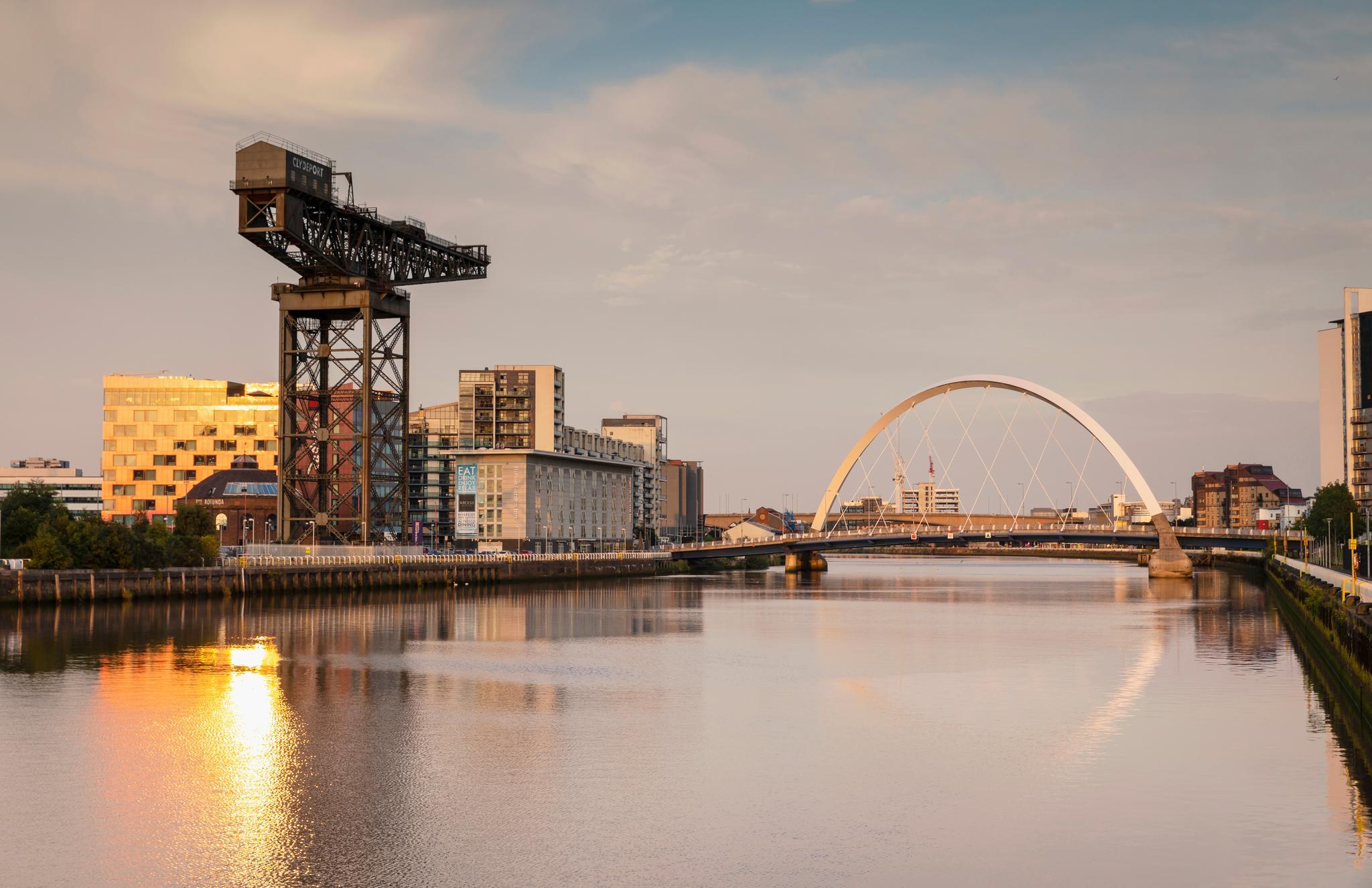 The sun is setting behind the large Finnieston Crane as we look down the river to the Clyde Arc
