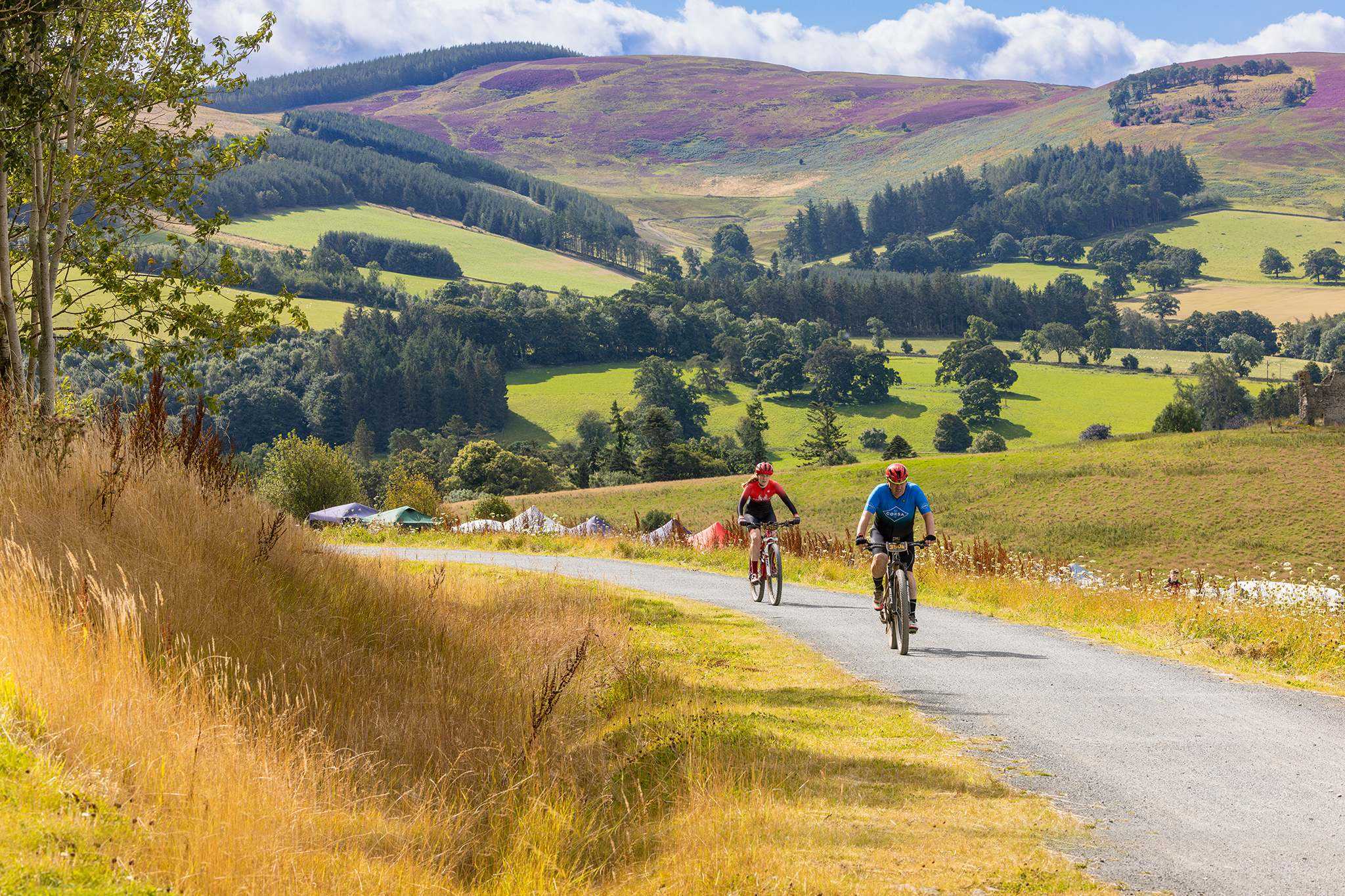 two cyclists on a quite country road with hills and fields in background