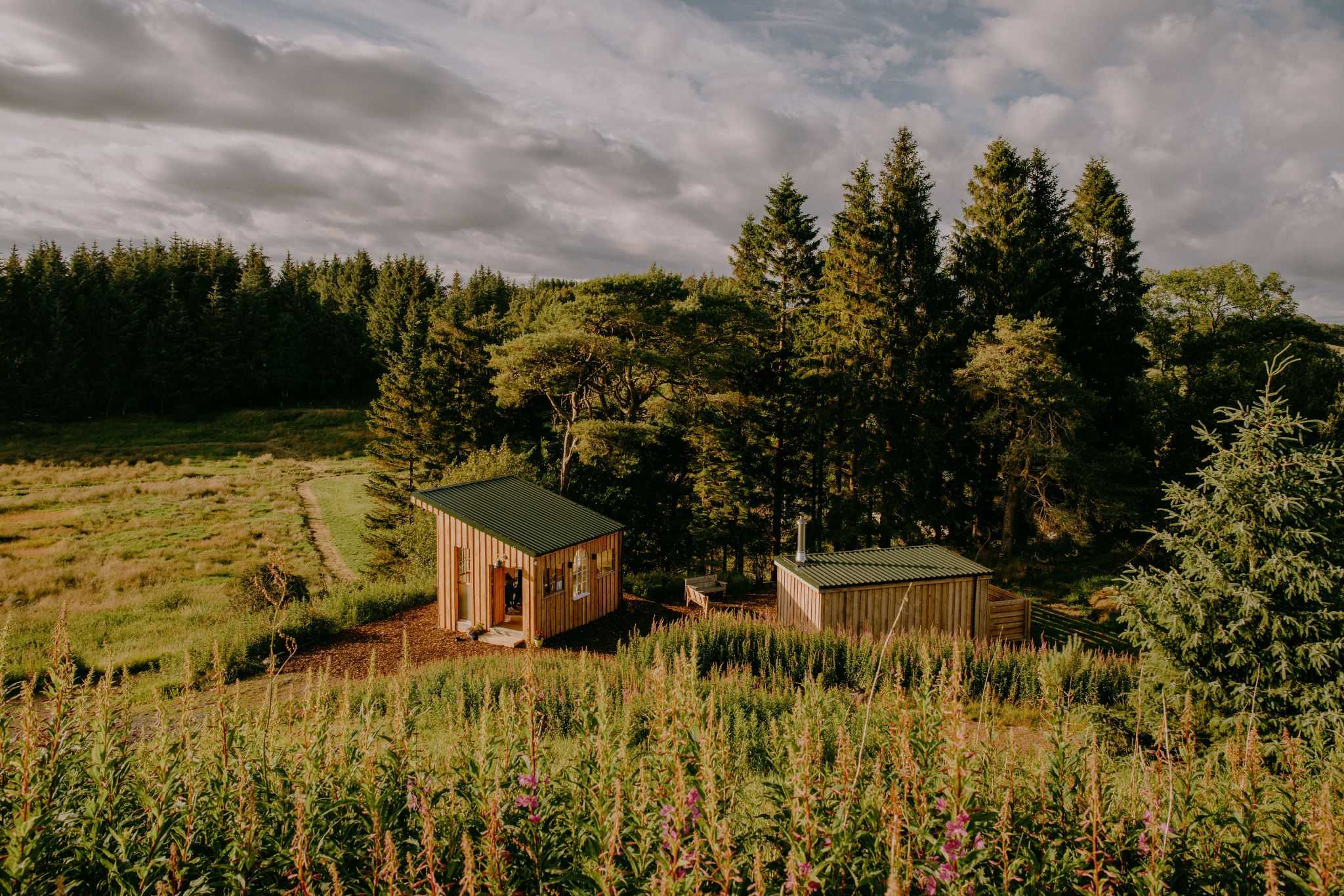 trees and fields surrounding a wooden sauna buildings