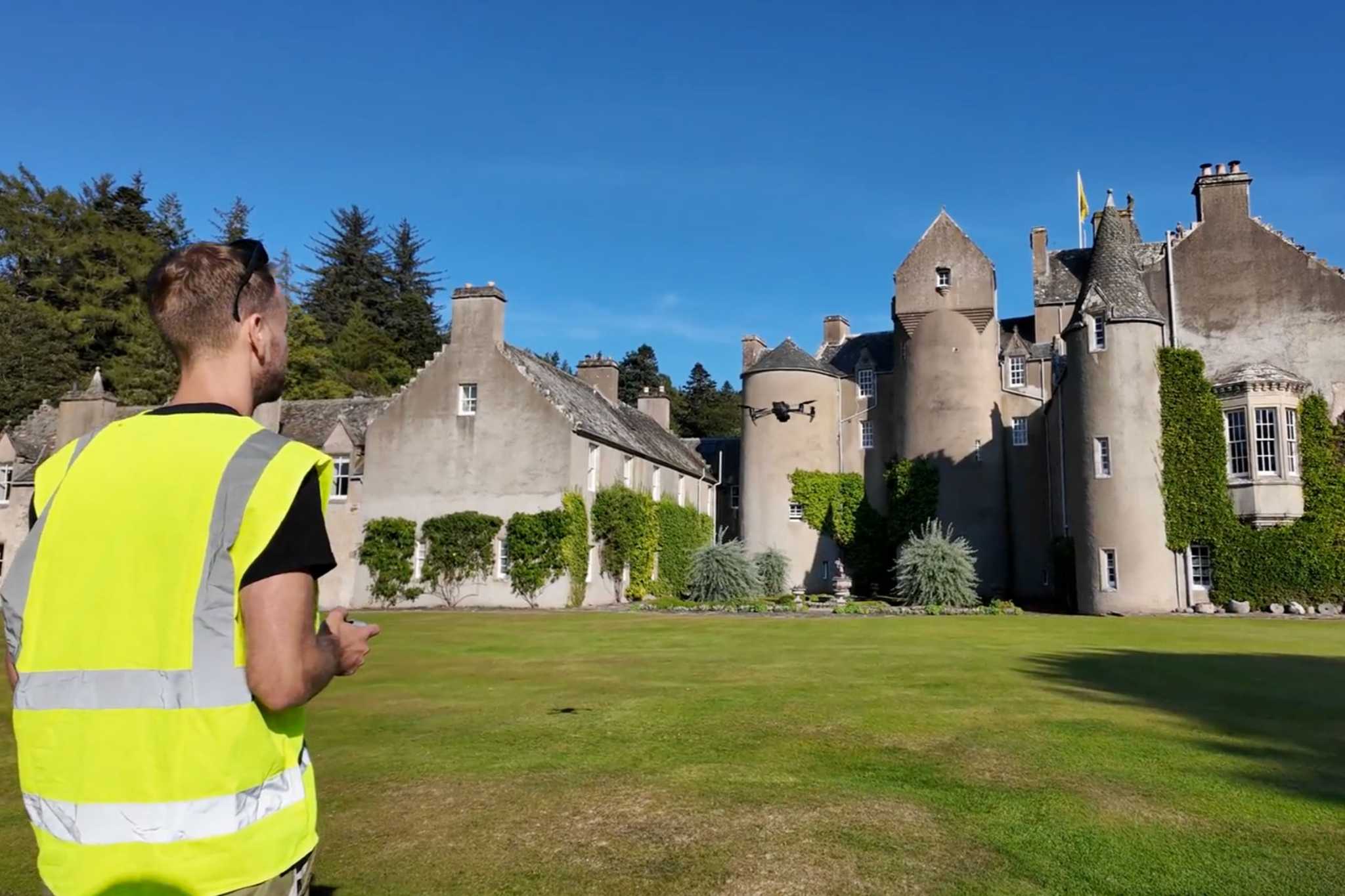 A man in a high vis vest stands in front of a castle.
