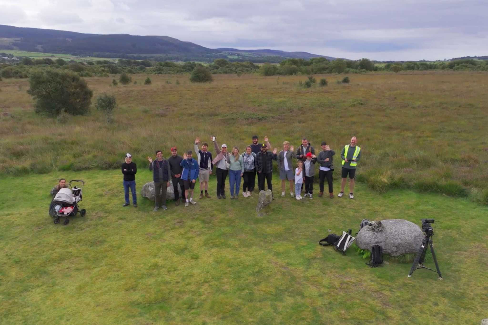 A large group of people wave at the camera.