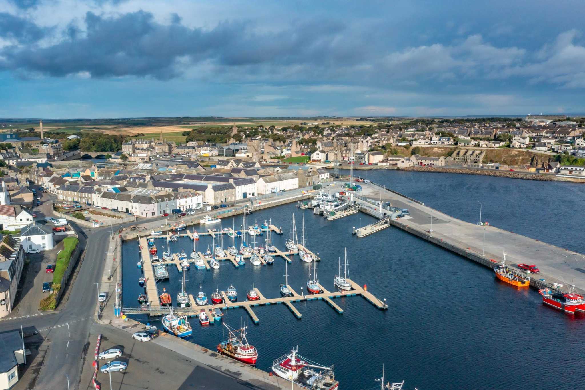An aril shot looking down over wick bay on a clear day. Boats are in the harbor.
